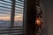 Handmade dreamcatcher hanging by the window with blinds in sunset twilight. Black silhouette of traditional magic amulet for dream