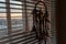 Handmade dreamcatcher hanging by the window with blinds in sunset twilight. Black silhouette of traditional magic amulet for dream