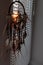 Handmade dreamcatcher hanging by the window with blinds in sunset twilight. Black silhouette of traditional magic amulet for dream