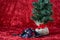 Handmade fabric face mask with a holiday print, with a burlap ball artificial tree, on a red background