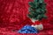 Handmade fabric face mask with a holiday print, with a burlap ball artificial tree, on a red background