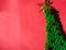 Handmade green knitted Christmas tree with a gold tinsel star on top and small pine cones. Beautiful red gradient Christmas