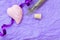 Handmade heart shaped lavender soap on a violet crumpled paper background with a glass flask with lavender flowers and ribbo