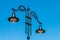 Handmade metal street lamp with vintage forms and led bulbs in park over blue sky