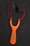 Handmade orange slingshot catapult. Y-shaped wooden stick with elastic tied between two top parts. Slingshot or Catapult is a