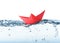 Handmade red paper boat floating on clear water against white background