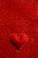 Handmade soft stitched felt heart on red shiny background, sequins in the side. The concept for Valentine`s Day. Copy space