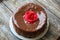 Handmade sponge cake with chocolate frosting. Small cake with cacao ganache glaze. Red sugar rose decorated. Homt pastry. Sweet