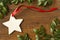 Handmade, star-shaped blank Christmas gift tag with red ribbon and natural evergreen decorations on rustic wood background