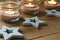 Handmade tea lights in jars with salt, wood decoration stars, close up, Christmas, New Year, advent