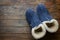 Handmade warm house shoes from sheepskin and sheep fur on weathered wood background. Winter autumn eco fashion clothing