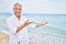 Handosme hispanic man with grey hair smiling happy at the beach, enjoying holidays pointing at copy space