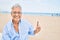 Handosme hispanic man with grey hair smiling happy at the beach, enjoying holidays pointing with finger at copy space