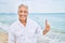 Handosme hispanic man with grey hair smiling happy at the beach, enjoying holidays pointing with finger at copy space