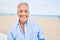 Handosme hispanic man with grey hair smiling happy at the beach, enjoying holidays on summer