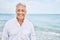 Handosme hispanic man with grey hair smiling happy at the beach, enjoying holidays on summer