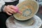 Handpainting on handmade decorative clay plate, craftsman`s hand paints a traditional pattern with enema, Podillya painting style