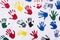 Handprints in yellow, blue, red, green, black on a white wall, background