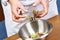 Hands adding lettuce leaves into bowl with salad, close-up