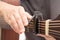 The hands are adjusting the capo to adjust the sound of the guitar.