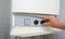 Hands adult men set the temperature of the water in the gas boiler.