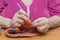 Hands of an adult woman close up. The woman knits with a hook and thread. Retired hobbies, handicrafts, handicrafts. Do-it-