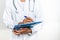 Hands of an afro female doctor writing on a paper with the help of a blue folder