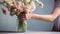 Hands arranging flowers in a vase by bright sunlight