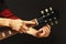 Hands of artist tunes the guitar on dark background