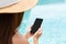 Hands of Asian woman using mobile phone at poolside. Relaxation, technology and lifestyle concept. Copy space, closeup