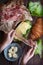 Hands assembling sandwich with croissant, meat, cheese, green salad, fresh cucumbers, flatlay