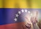 Hands on the background of the Venezuela flag. Freedom concept