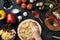 Hands of baker adding ingredients into pizza during pizza preparation at kitchen