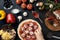 Hands of baker adding ingredients into pizza during pizza preparation at kitchen