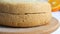 Hands of a baker cook woman with a knife cut an orange biscuit or sponge cake dough in the kitchen. Making Sweet