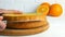 Hands of a baker cook woman with a knife cut an orange biscuit or sponge cake dough in the kitchen. Making Sweet