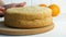 Hands of a baker cook woman with a knife cut an orange biscuit or sponge cake dough in the kitchen. Making Sweet