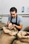 Hands of barrista putting green unroasted coffee beans into sack at factory