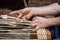 Hands of a basket maker are braiding a wicker basket