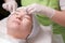 The hands of a beautician in white gloves wipe the girl skin with cotton pads. Close-up face of Asian woman on rejuvenation proced