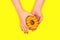Hands of a beautiful woman holds a sweet yellow donut. Flat lay.