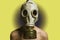 Hands behind his back, man in gas mask on a yellow background, naked torso