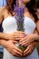 Hands on the belly of a pregnant woman, symbolizing future motherhood. A walk of a young couple on a lavender field, a cozy, quiet