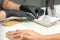 Hands in black gloves of manicurist preparing special nail file equipment for manicure treatment in a beauty salon.