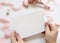 Hands with blank card near pink flowers and ribbons