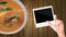 Hands with blank photo frame and tom yum kung (spicy shrimp soup) on wooden background