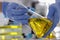 Hands in blue gloves hold flask with clear golden liquid in laboratory.