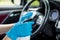 Hands with blue gloves then sprinkling disinfectant and cleaning the car