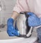 Hands in blue gloves wash the electric kettle