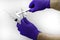 Hands in blue medical gloves hold two syringes of different diameters one of which measures the concept of drug dosage with a